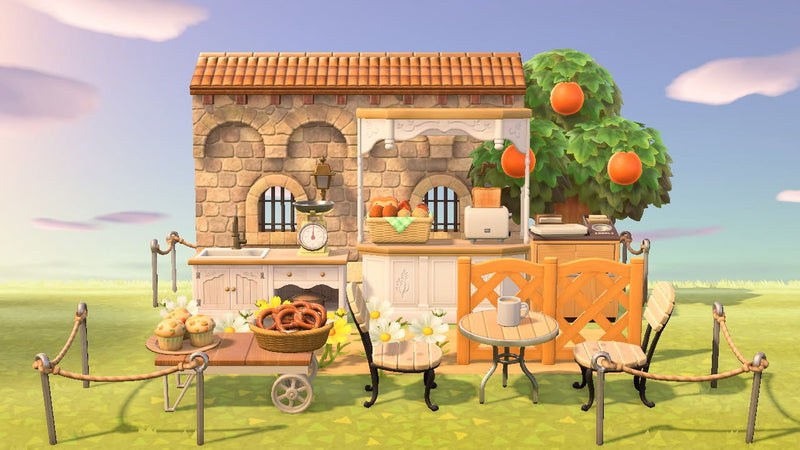 Animal Crossing Petite Bakery room design with a stone building, covered counter of bread, orange tree, cafe table and garden chairs behind a rope fence
