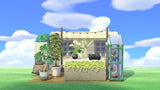Animal Crossing Mini Flower Set with a plant stall storefront under party lights, an anthurium in a black pot, seedling tray, monstera and potted greenery