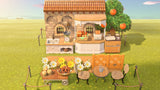 Second view of the ACNH Petite Bakery design showing the ranch kitchen, analog kitchen scale, pop-up toaster, busing station and a cart of pretzels and cupcakes